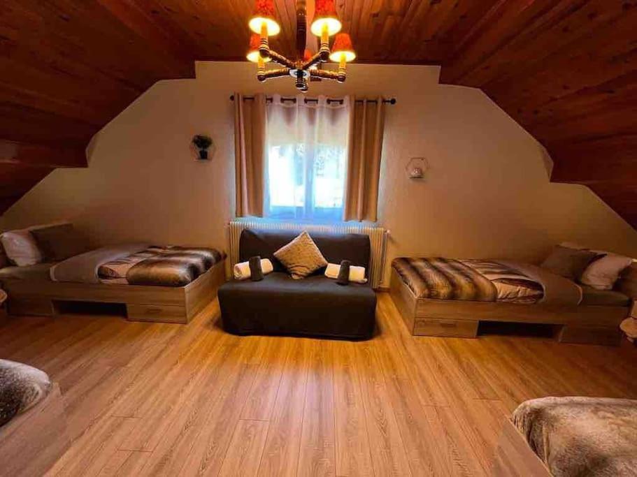 a attic room with two beds and a couch at EVASION gîtes et spa in Saint-Léonard