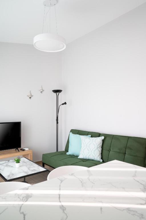 a living room with a green couch and a tv at Sarah Luxury Rooms in Syvota