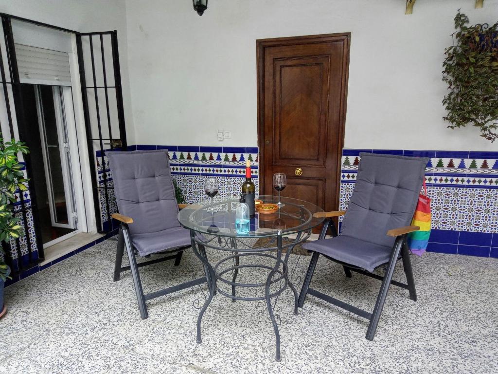 ヘレス・デ・ラ・フロンテーラにあるCasa Valientes A - Free private parking, WiFi & ACのガラステーブル(椅子2脚付)、ワイン1本
