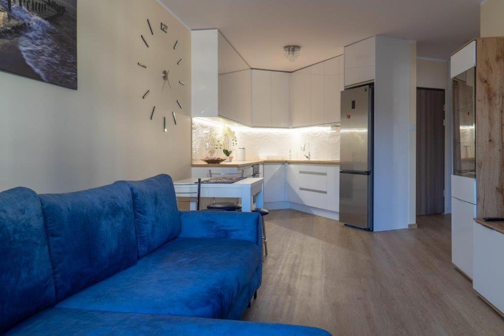 a living room with a blue couch and a kitchen at Apartament przy Czarnej in Białystok