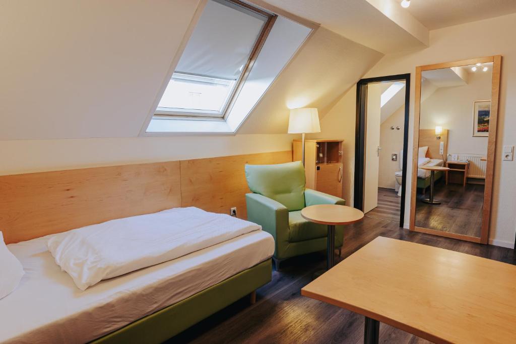 a bedroom with a bed and a chair and a table at Hotel-Restaurant Zum Schwanen in Wermelskirchen