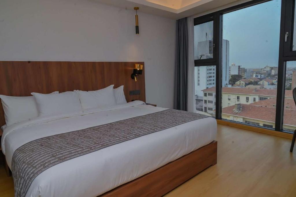 a bedroom with a large bed and a large window at AXIL HÔTEL in Dakar