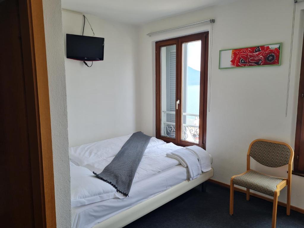 a bedroom with a bed and a window and a chair at Zappa Lake Lodge in Brusino Arsizio