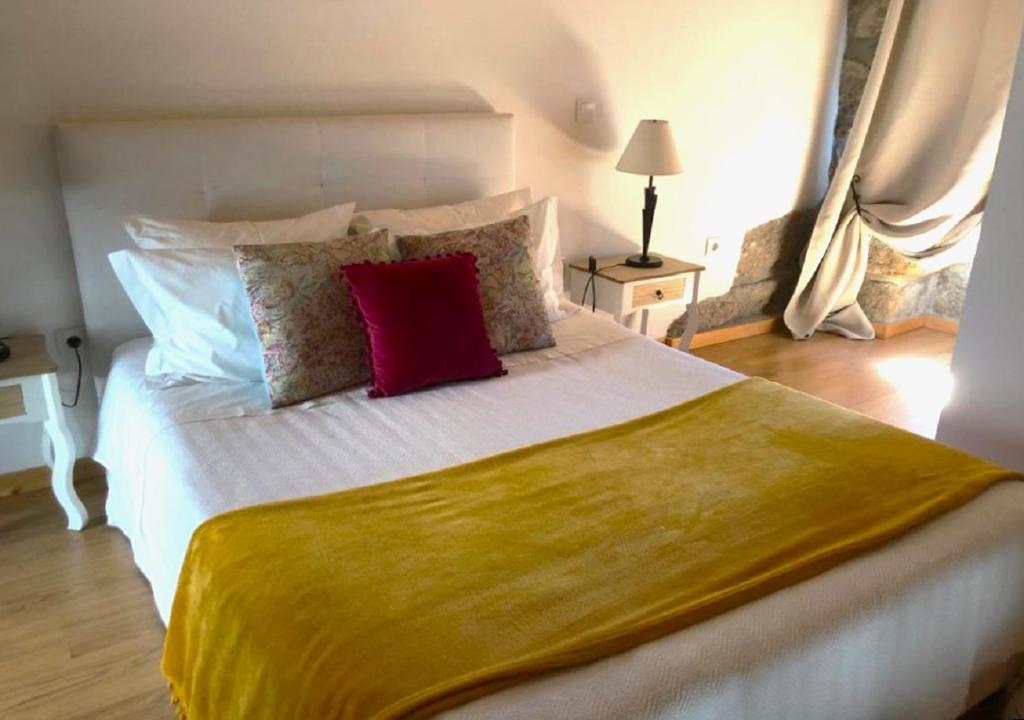 a bedroom with a large white bed with red pillows at Casinha da Raposeira in Soajo
