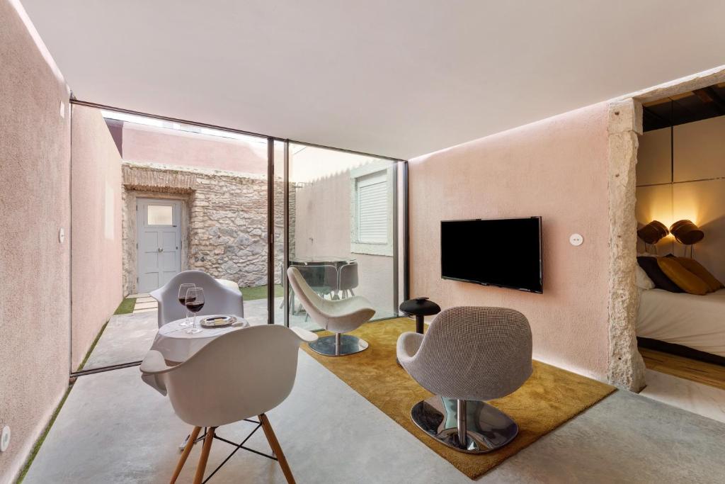 een woonkamer met stoelen en een tv en een bank bij Lxfactory Terrace Lisbon Loft in Lissabon