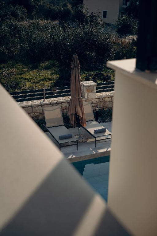 a patio umbrella and chairs next to a pool at Sarah Luxury Rooms in Syvota