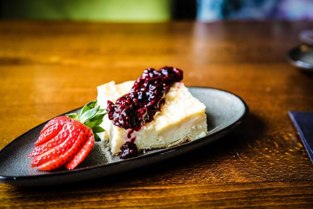 un morceau de gâteau et de fraises sur une plaque sur une table dans l'établissement The Roundabout Hotel, à Pulborough