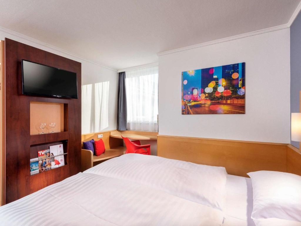 メルズンゲンにあるibis Kassel Melsungenのベッド1台、薄型テレビが備わるホテルルームです。
