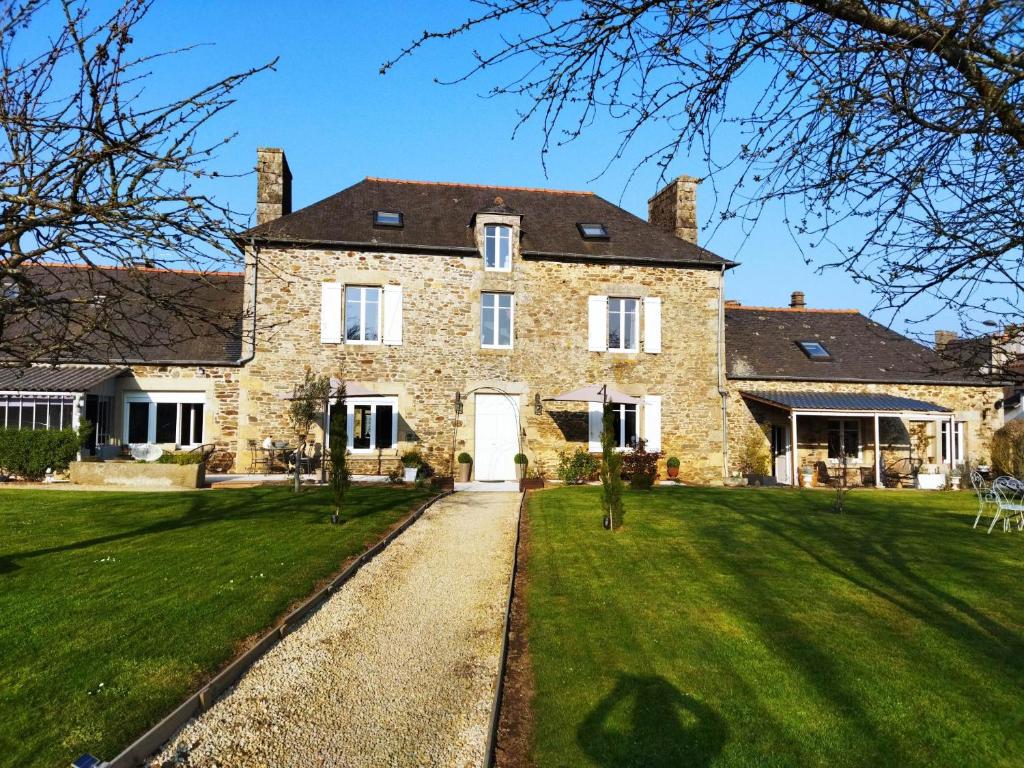 a large stone house with a green lawn at La Ménardière Serenitatis chambre d'hôtes petit déjeuner compris in Corseul