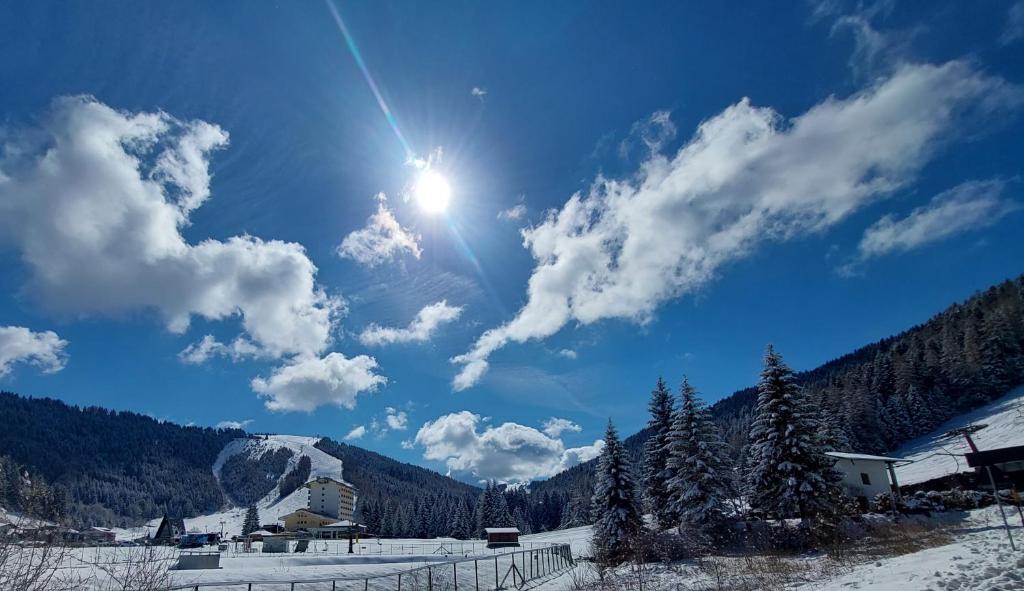 un sol brillando en el cielo sobre una montaña cubierta de nieve en Rifugio Di Pace en Folgaria