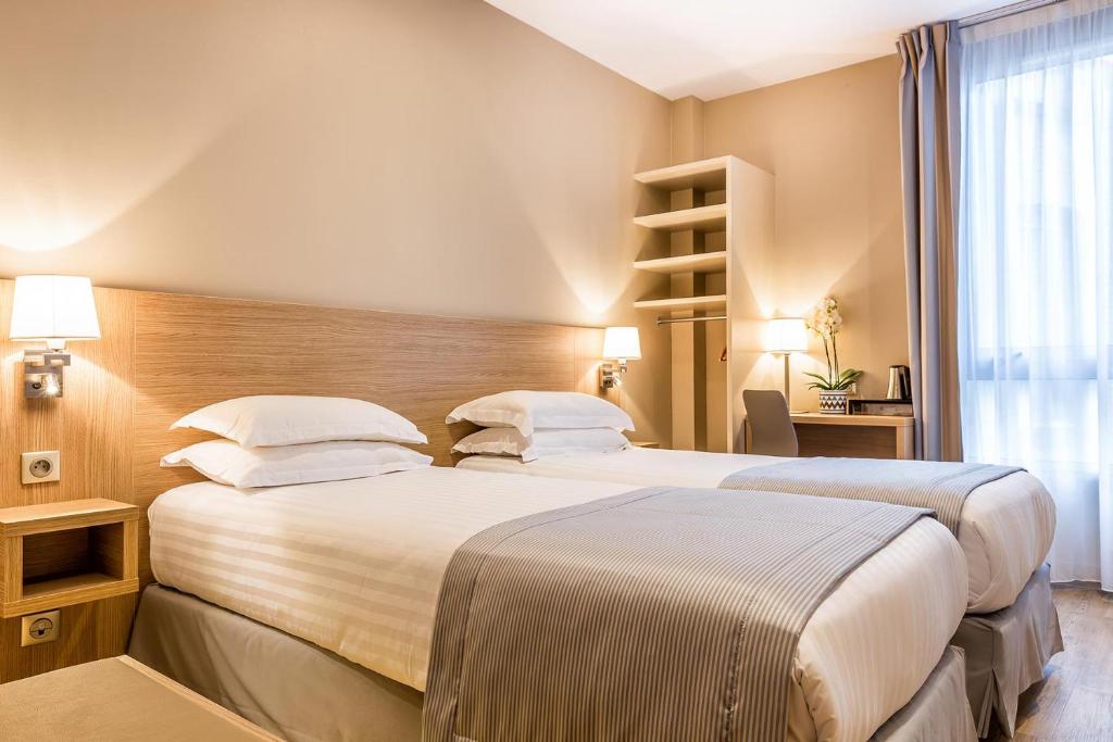 a hotel room with two beds and a window at Hôtel Saint Albert in Sarlat-la-Canéda