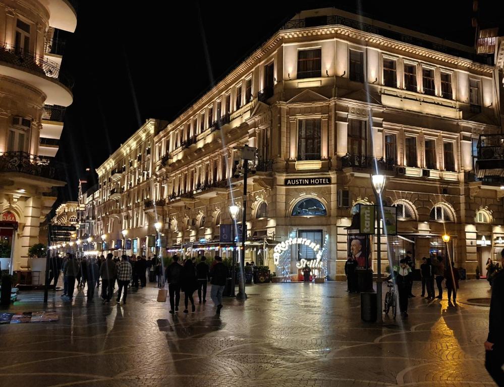 un grupo de personas caminando por una calle de la ciudad por la noche en Austin Hotel Baku en Baku
