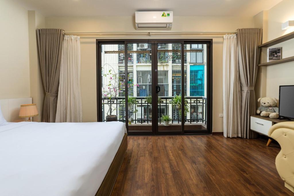 a bedroom with a bed and a sliding glass door at YR Hotel & Apartments in Hanoi