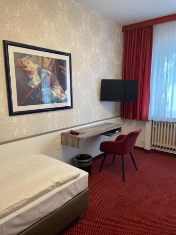 Habitación de hotel con cama, silla y escritorio. en Hotel Germania, en Colonia
