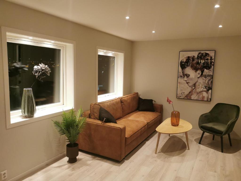 Una sala de estar con un sofá marrón y una mesa. en Hurthi Apartment - Blue House, en Vardø