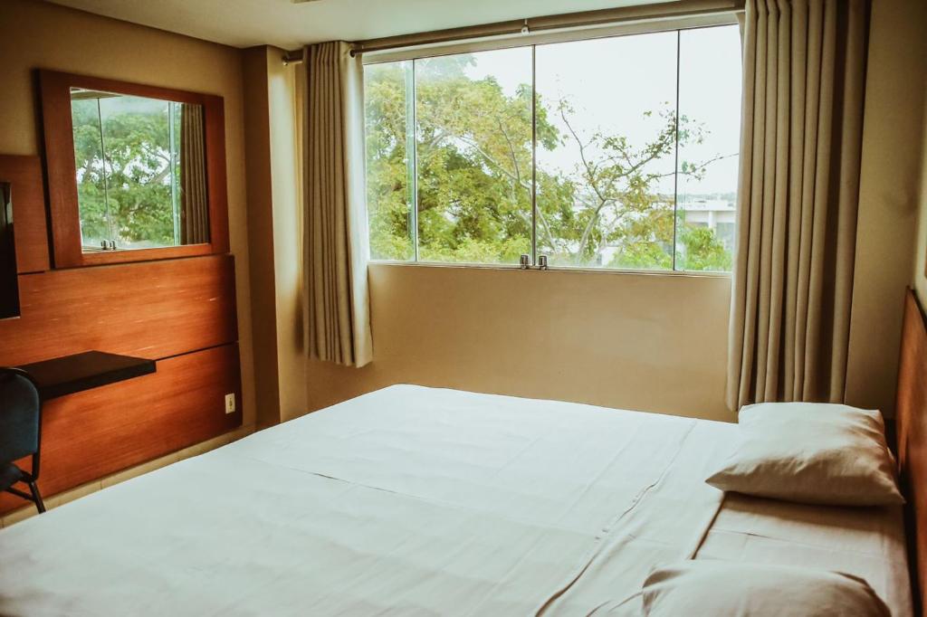 a bedroom with a bed and a large window at Barrudada Tropical Hotel in Santarém