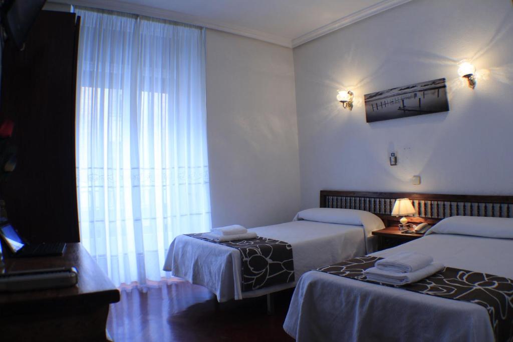 a hotel room with two beds and a window at Hostal Esmeralda in Madrid