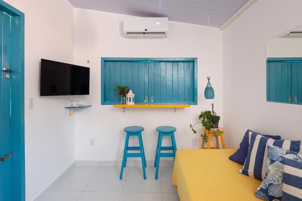 a living room with two blue stools and a couch at Pipa Magnólia Chalés in Pipa