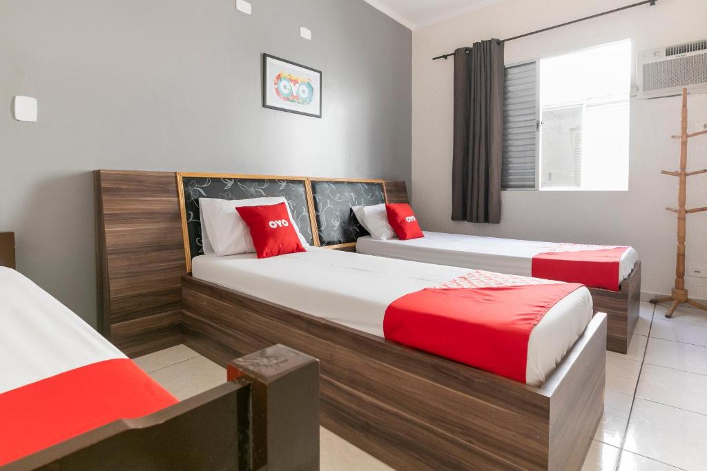 two beds in a room with red and white at OYO Hotel Sunshine in São Bernardo do Campo
