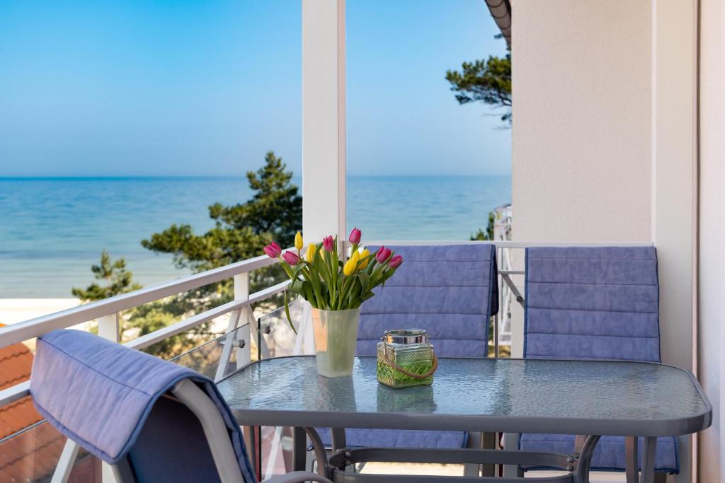 a table with a vase of flowers on a balcony at Nixe - Villa Helene mit Meerblick in Top Lage in Binz