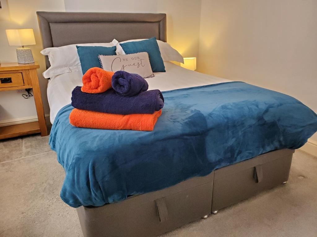a bed with blue and orange towels on it at Ipswich Town Centre Apartment 5 in Ipswich