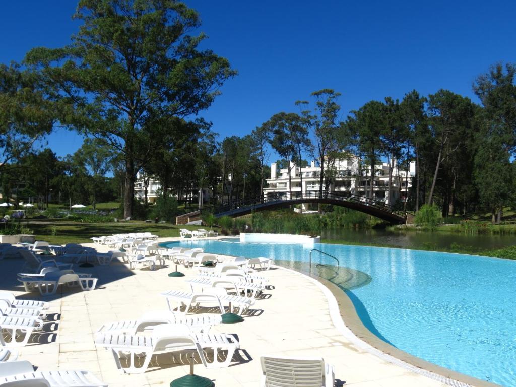 a swimming pool with white chairs and a bridge at Green Park Propietarios in Punta del Este