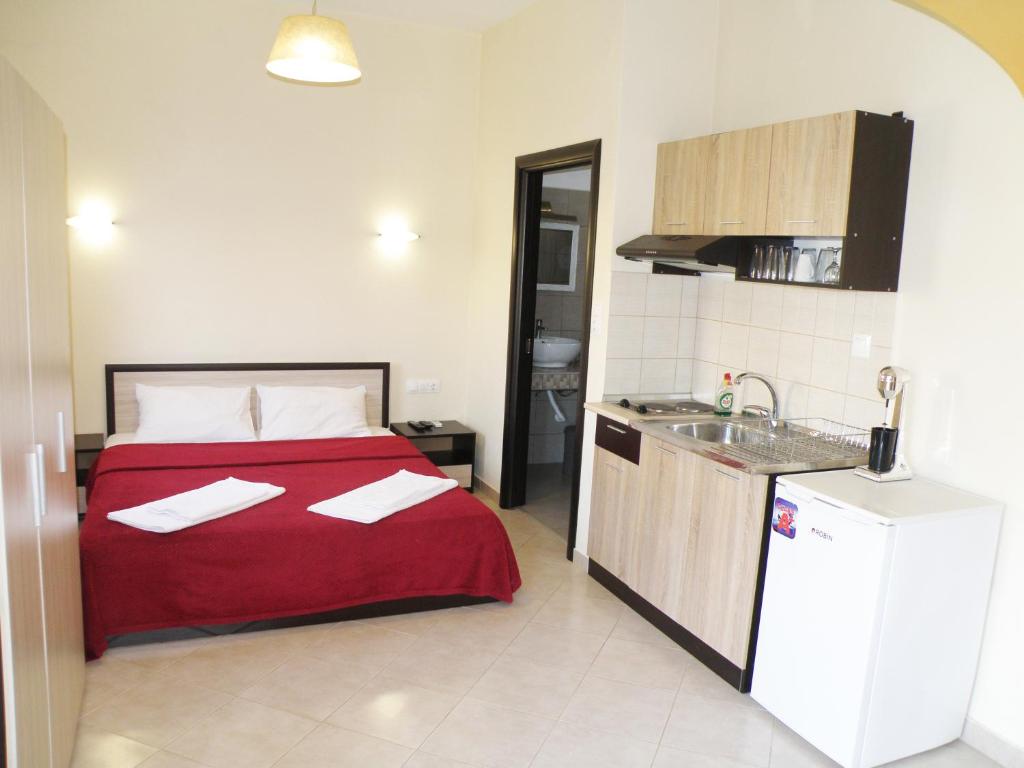 a bedroom with a bed with a red blanket and a kitchen at Thassosrent in Limenaria