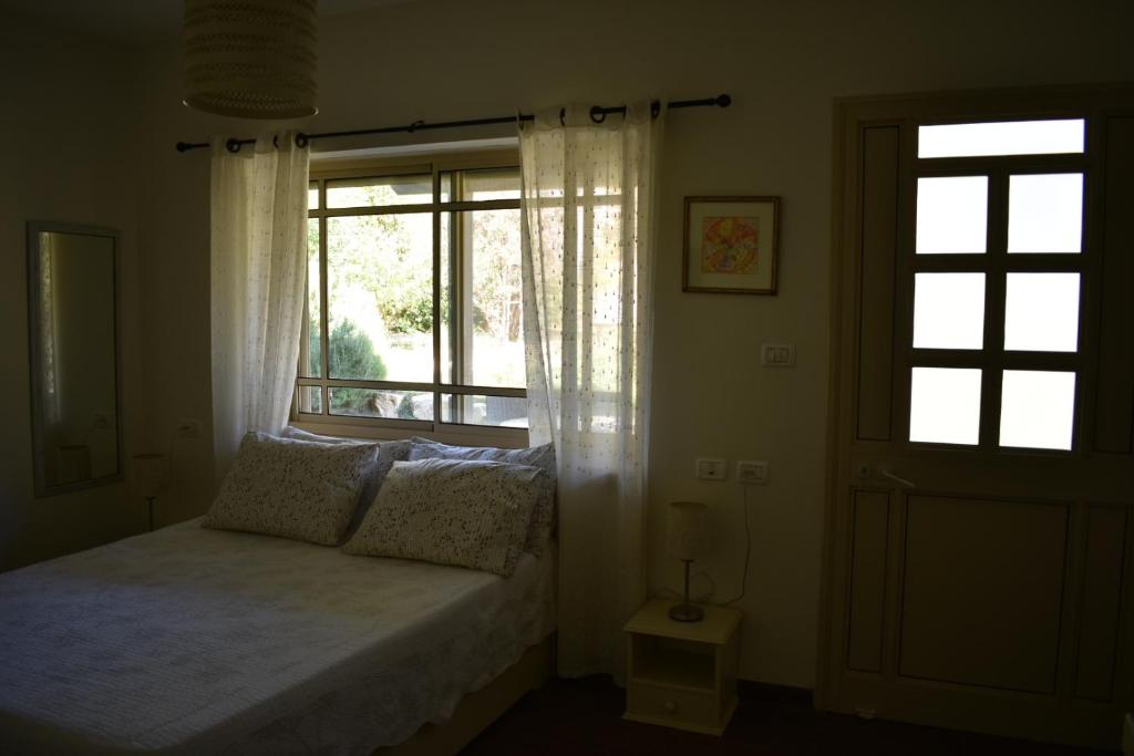 a bedroom with a bed in front of a window at Rothschild Galilee Hospitality in HaGoshrim