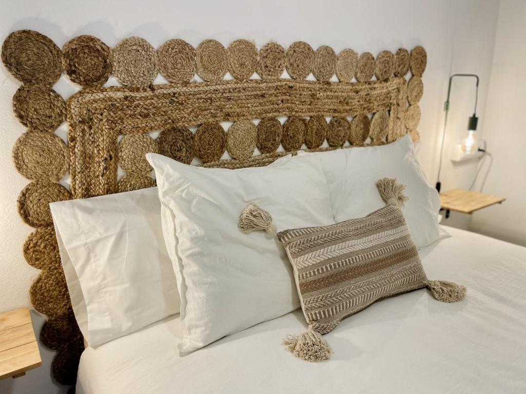 a bed with a brown headboard and white pillows at Apartamentos Carabela in Playa Migjorn