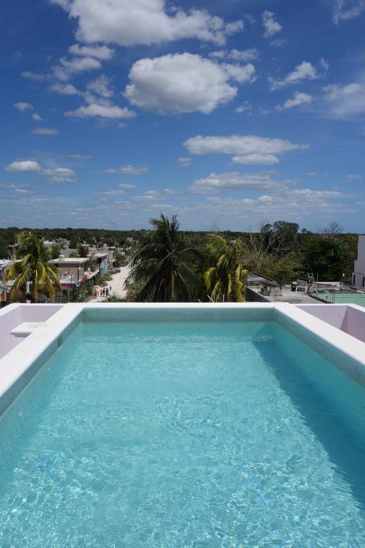 a pool with a view of the beach and palm trees at Itza Hotel Akumal in Akumal