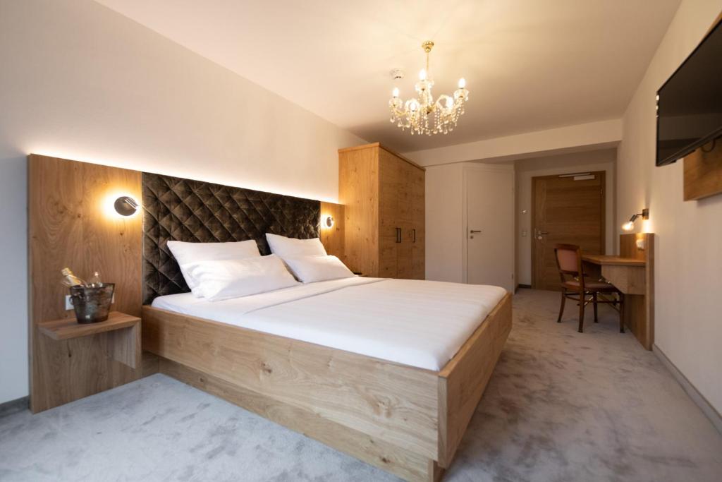 a bedroom with a large bed and a chandelier at Thurners Boutique Hotel in Bruck an der Großglocknerstraße