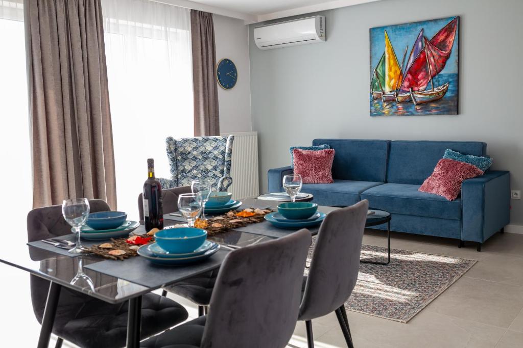 une salle à manger avec une table et un canapé bleu dans l'établissement Darłówko Apartament Morski X, à Darłówko