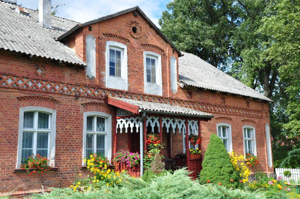 a red brick house with flowers in the front yard at Dom Gościnny in Gietrzwałd