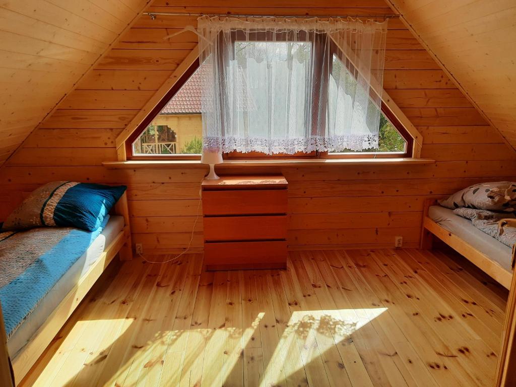 a bedroom with two beds in a wooden cabin at Domki nad Stawem w Rynie in Ryn