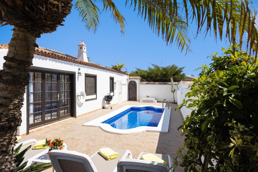 un patio trasero con piscina y una casa en CASA GOLF beautiful views with private pool, en San Miguel de Abona