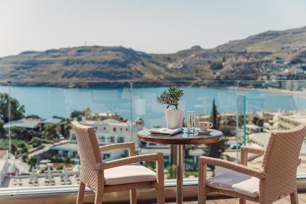 a table and chairs on a balcony with a view of the water at Lindos Village Resort & Spa Adults Only in Lindos