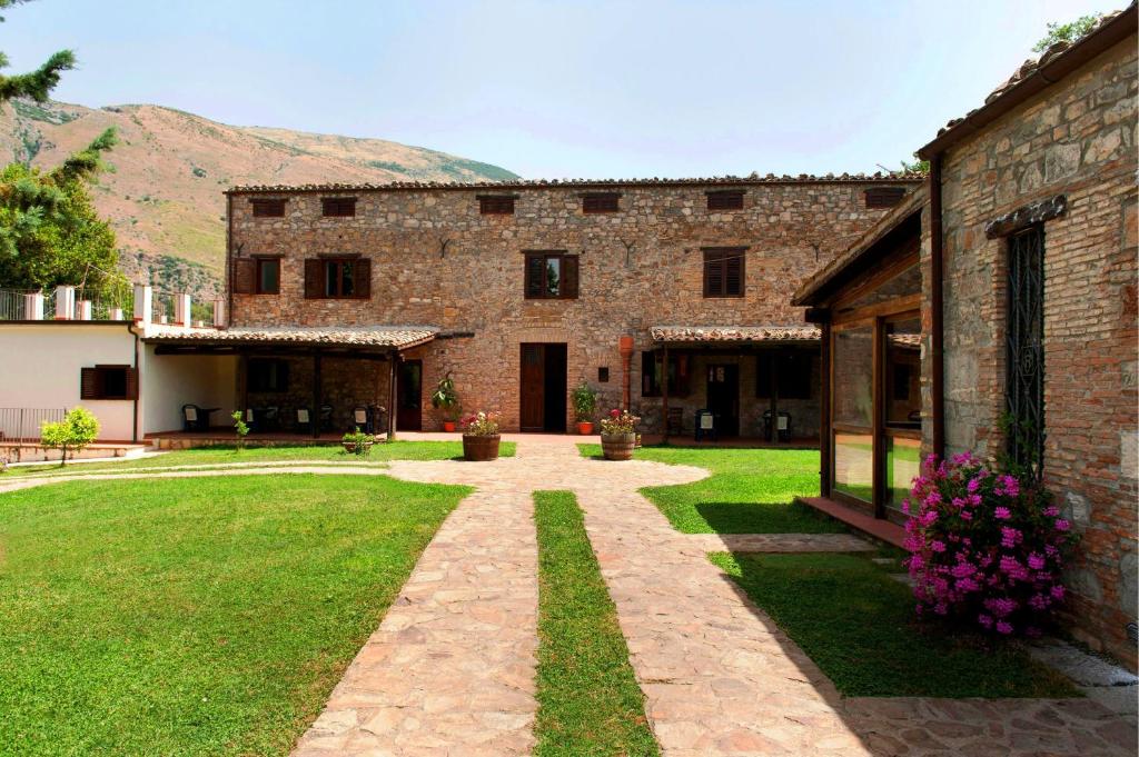 a large brick building with a grass yard at L'Antico Casale in Polizzi Generosa