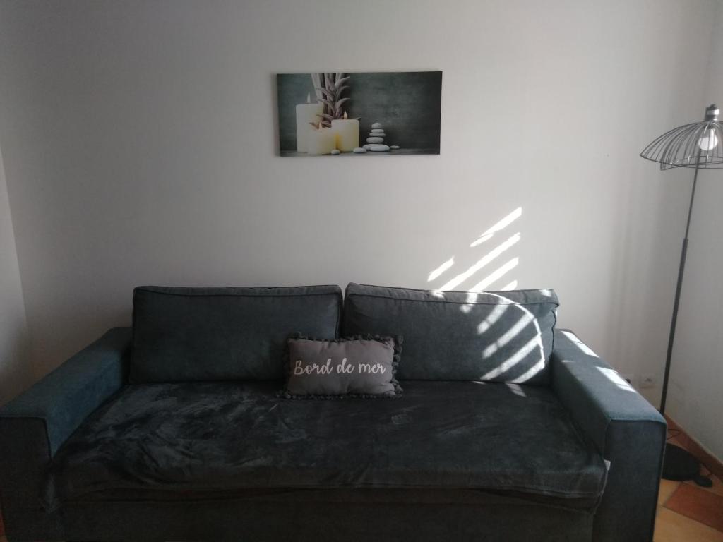 um sofá com uma almofada na sala de estar em La Terrasse em Mers-les-Bains