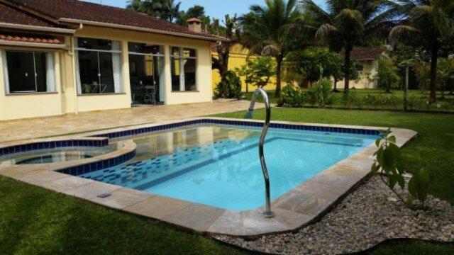 a swimming pool in front of a house at Encantadora Chácara com Piscina em Itanhaém in Itanhaém