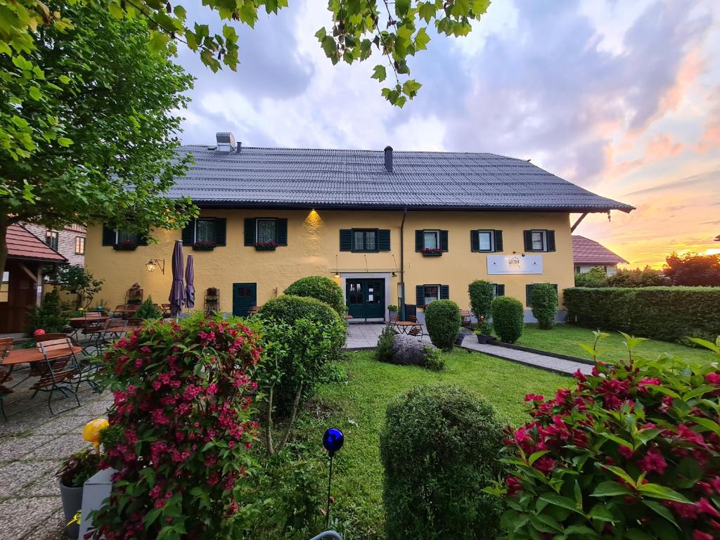 une grande maison avec une cour fleurie dans l'établissement Gasthof zur Strass, à Eugendorf