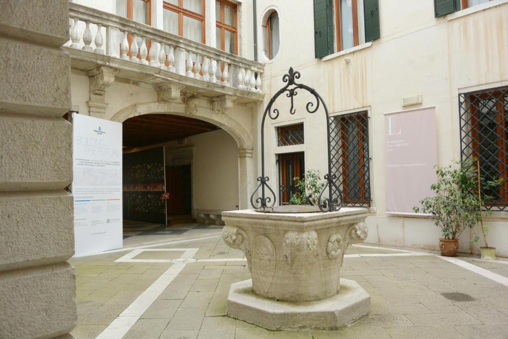 a fountain in front of a building with a clock on it at Foresteria Levi in Venice