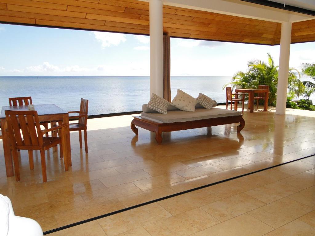 eine Veranda mit einem Tisch, Stühlen und Meerblick in der Unterkunft Ocean Breeze Villa in Tevaitoa