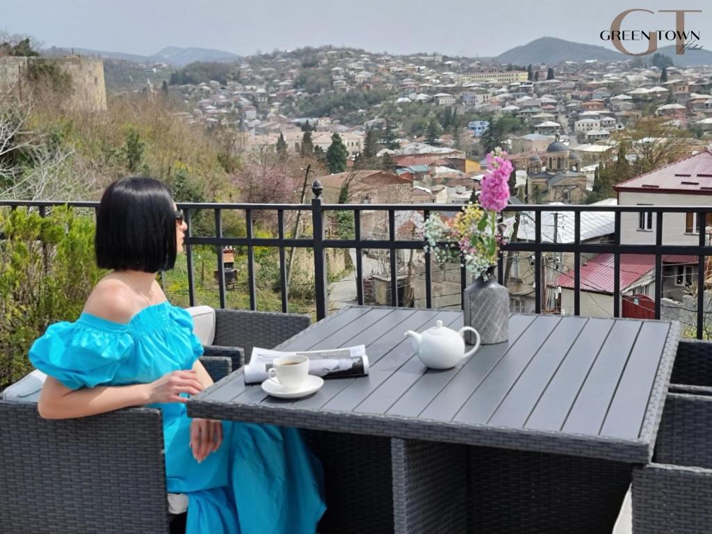 Una mujer con un vestido azul sentada en una mesa en Hotel Green Town, en Kutaisi