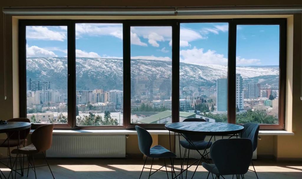 ein Zimmer mit Tischen und Stühlen und einem großen Fenster in der Unterkunft Phazisi Hotel in Tbilisi City