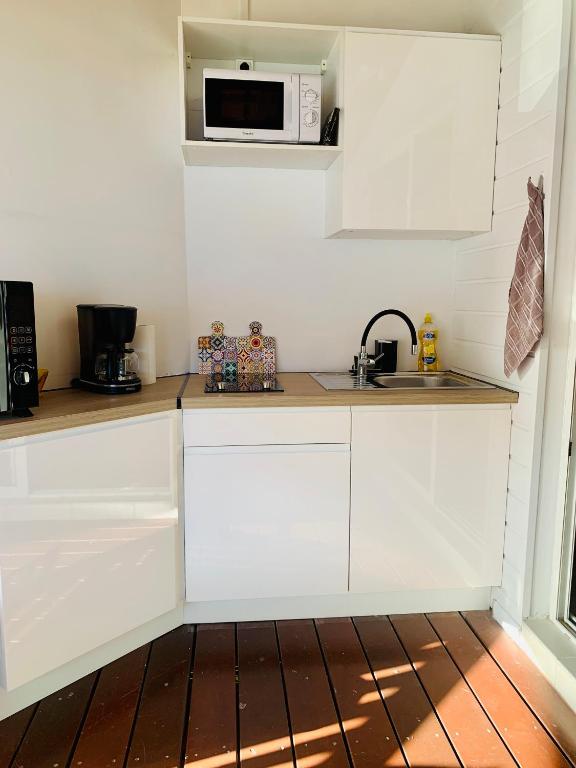 uma cozinha com armários brancos e um micro-ondas em SOMPTUEUX DUPLEX SUR LA ROUTE DES PLAGES em Sainte-Anne