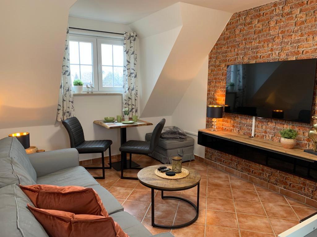 een woonkamer met een bank en een open haard met een tv bij Frische Brise in Insel Poel