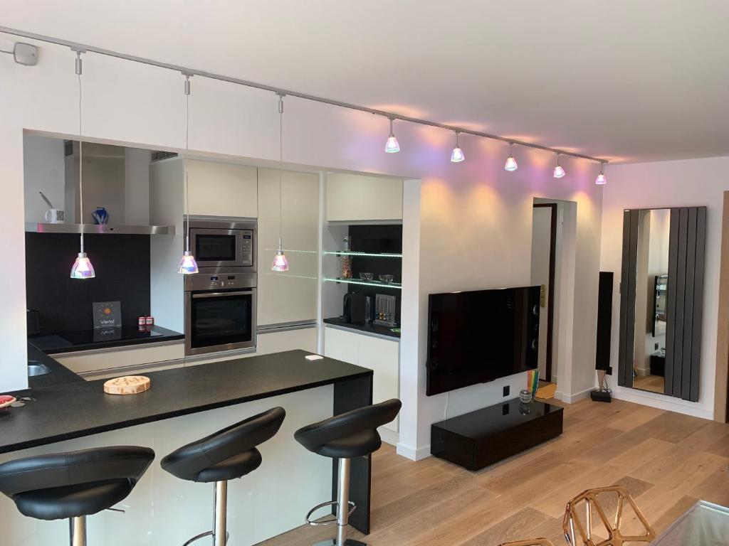 a kitchen with a bar with stools and a tv at Appartement design en plein centre du Touquet in Le Touquet-Paris-Plage