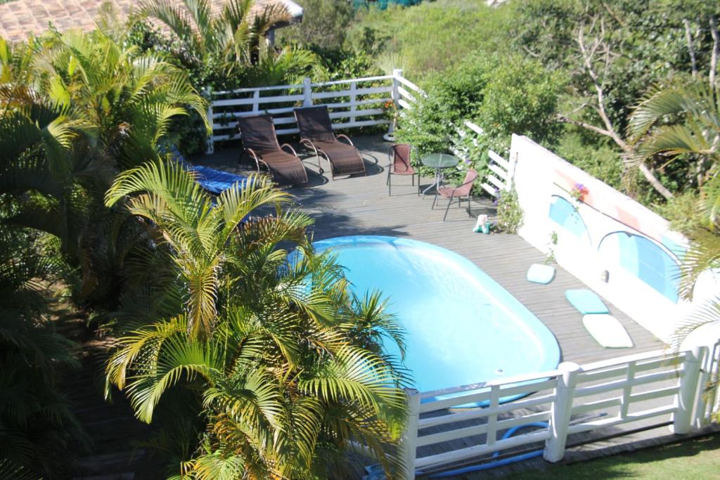 a deck with chairs and a swimming pool at Pousada Sonho do Vale in Praia do Rosa