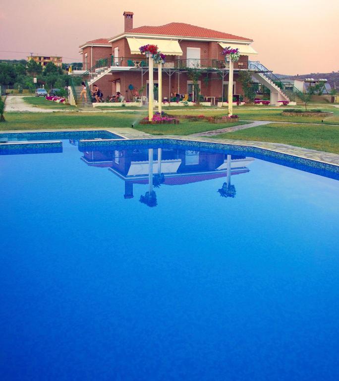 a swimming pool with blue water in front of a house at Kiki's Place in Nikiti