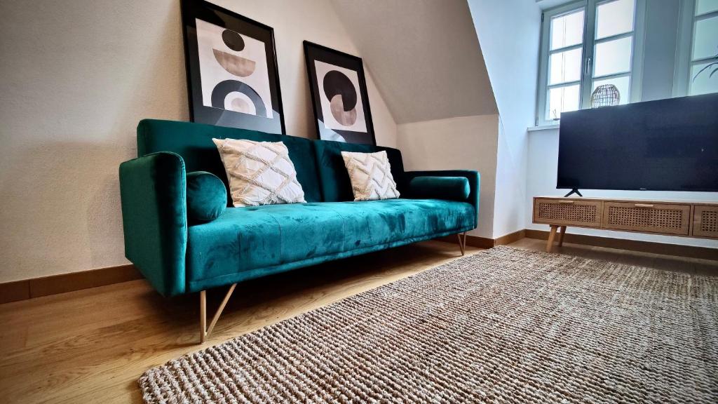 un sofá verde en una sala de estar con TV en One Apartment's⎢Neu+Zentral⎢Alberstplatz⎢Altbau, en Coburg